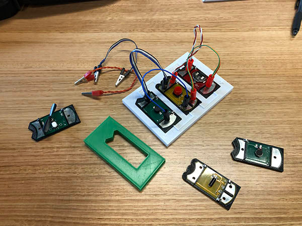 3 PCBs in a white template. There are banana plugs and cables connecting the board together