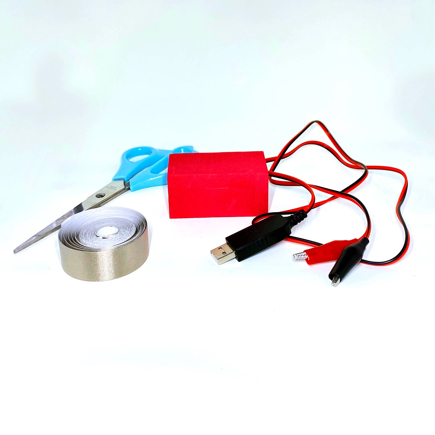 Usb plug cable and black and red alligator clips, sitting with a red foam block, conductive tape and scissors