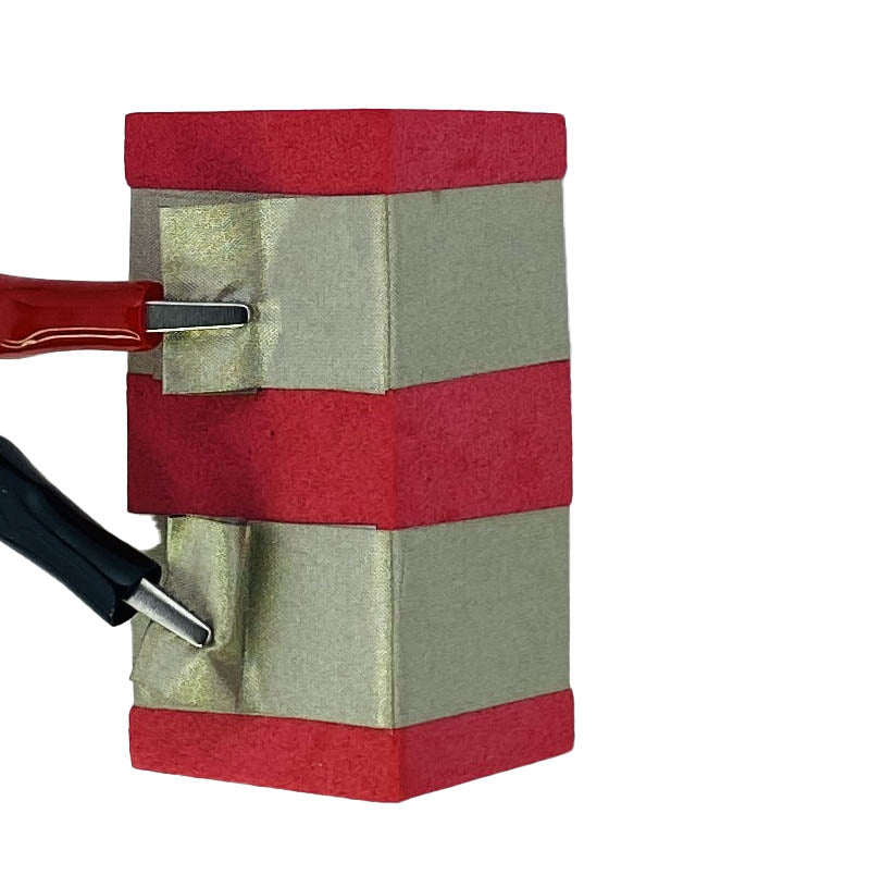 Red power TapeBlock with a red and black alligator clip attached to the two lines of conductive tape