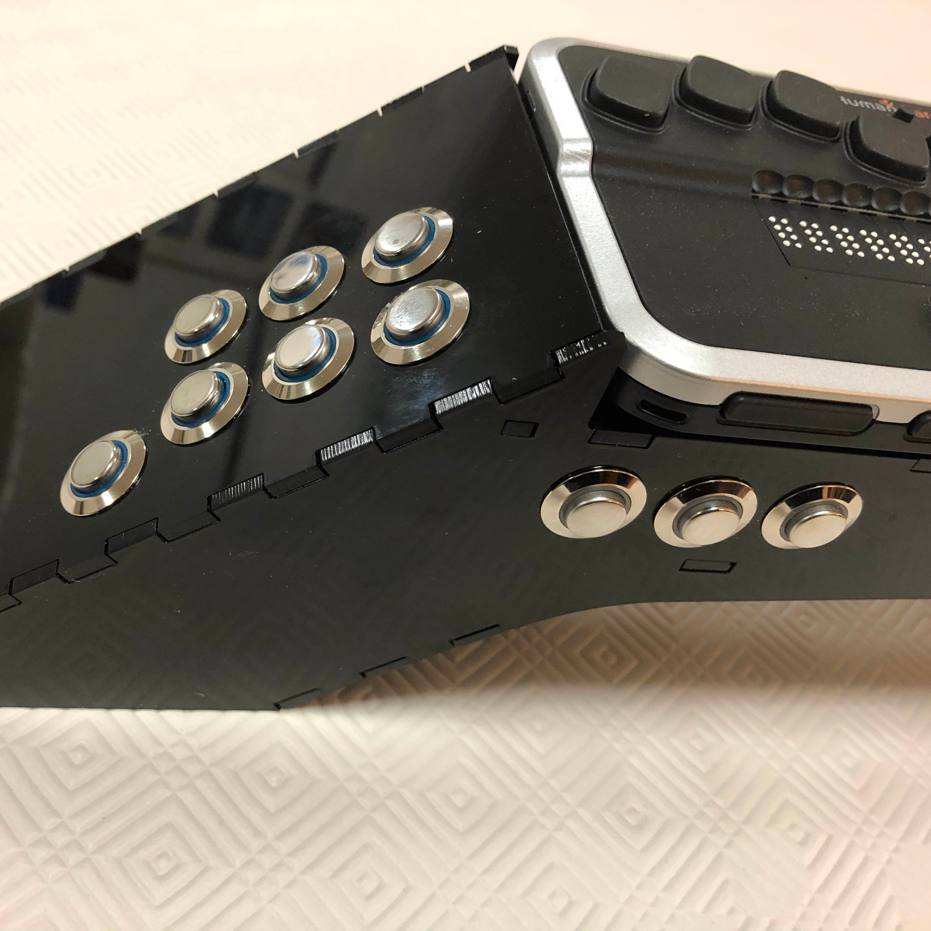 A close up of the end with 7 buttons on the end and three on the front. A braille display is on the top