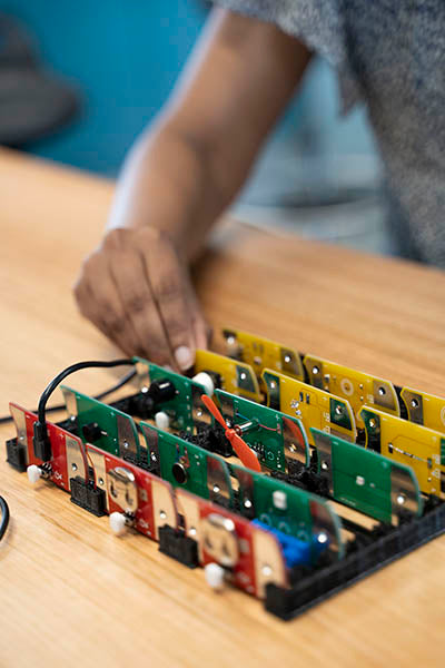 Five rows of simple circuit boards with a hand reaching towards them