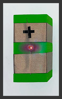 Foam block with two rows of conductive tape. Blue and Red Light Flashing. Plus symbol on top row of tape indicates direction