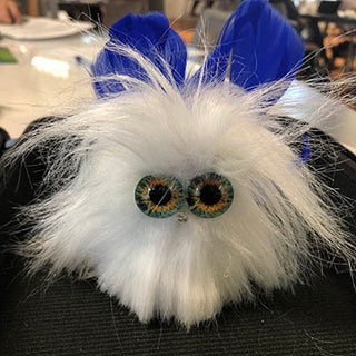 A White fur TapeBlock with large glass eyes and blue feather wings