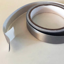 Load image into Gallery viewer, A 5 meter roll of conductive tape with an inch of the silver conductive tape separated from the white backing
